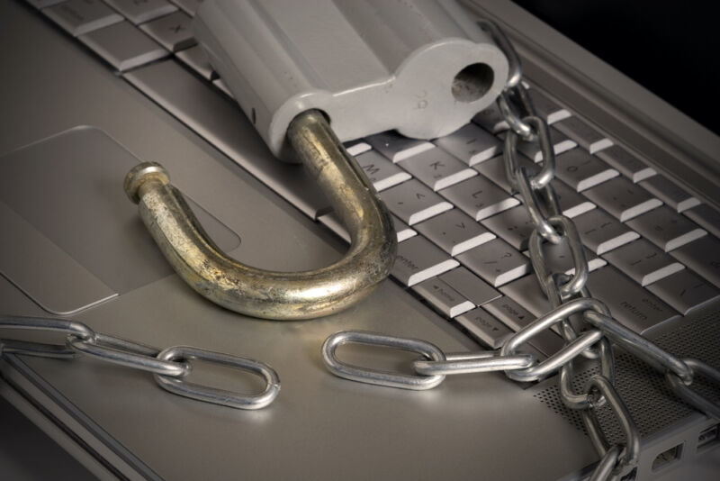 A chain and a padlock sit on a laptop keyboard.