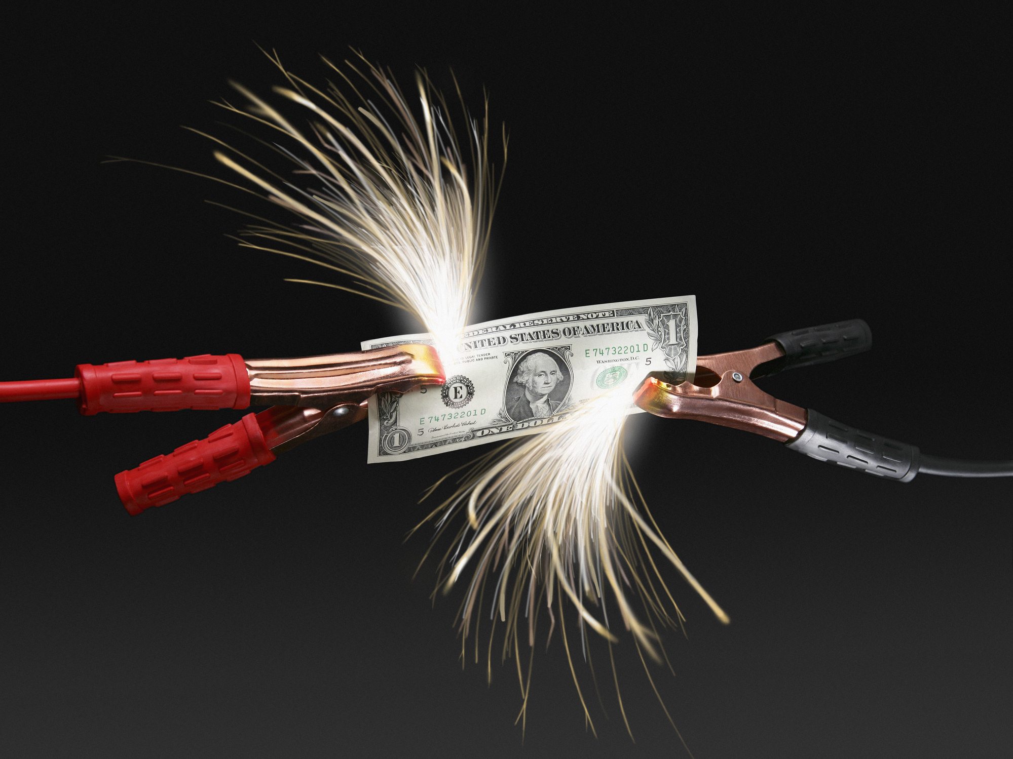Sparks coming off US dollar bill attached to jumper cables