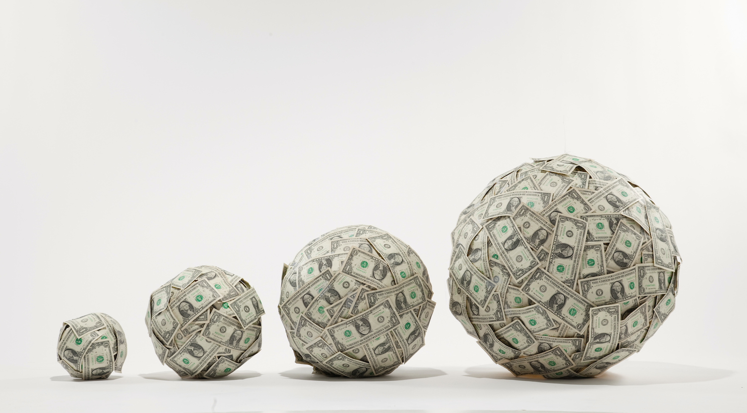 4 progressively larger balls of US $1 bills, studio shot