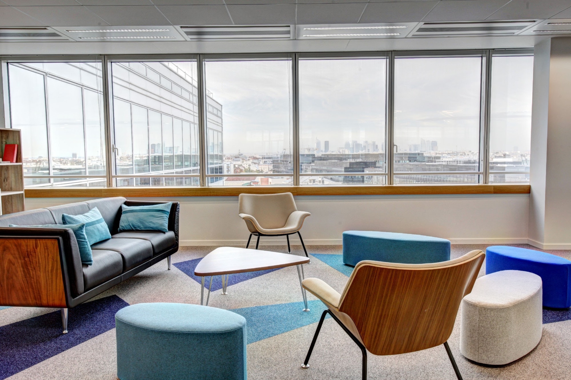 empty chairs arrayed around a contemporary coffee table in a vacant conference room with a city view through windows in the background