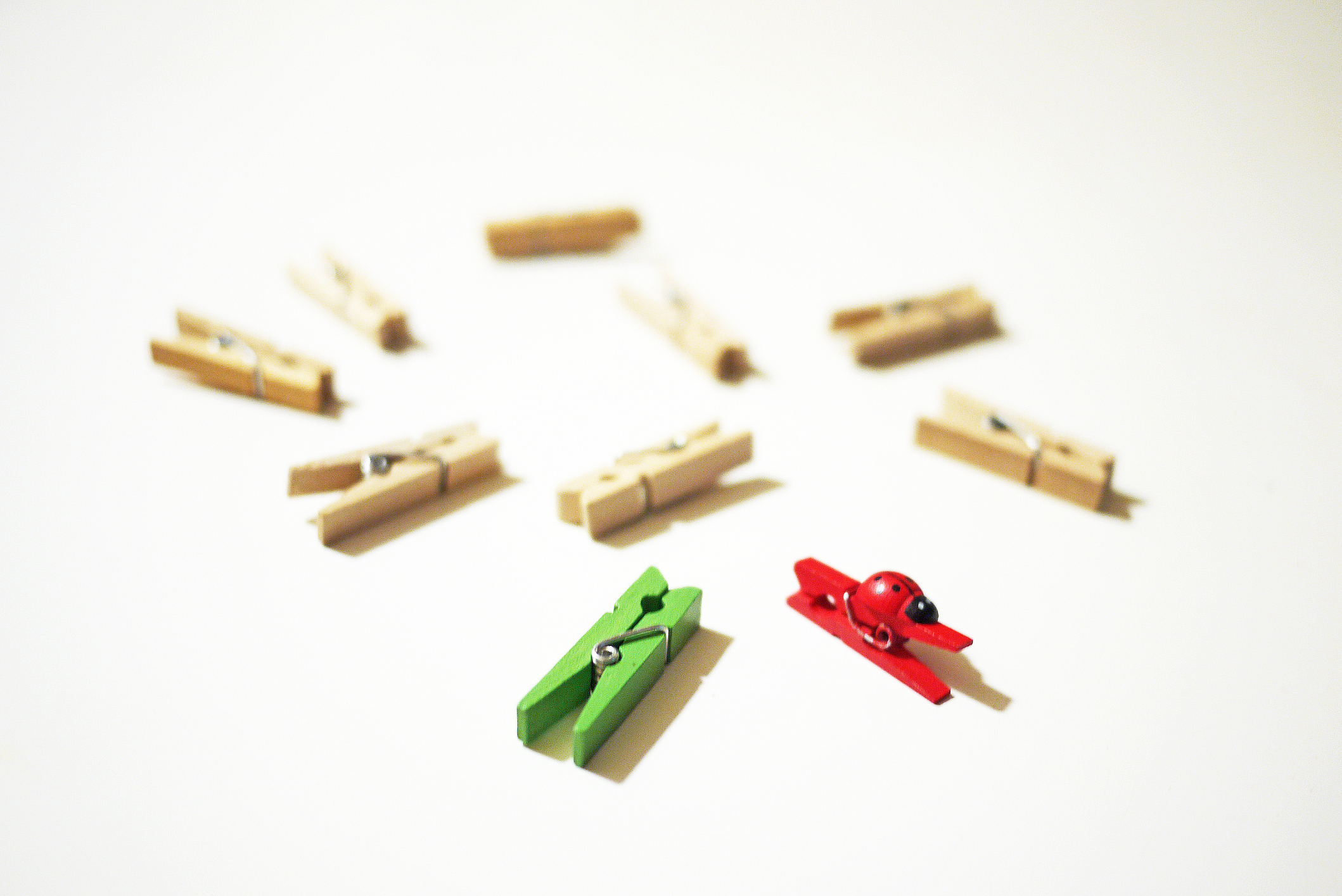 Scattered clothes pegs with red and green ones pushing forward