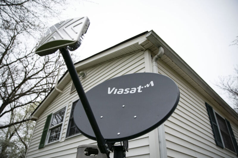 Satellite dish with a private residence and a gray sky in the background.