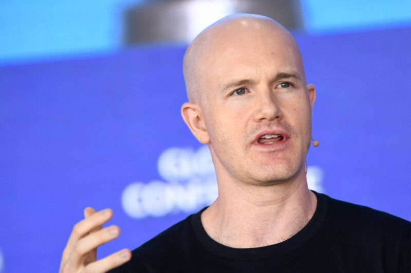 Coinbase CEO Brian Armstrong speaking at a conference and gesturing with his hand.
