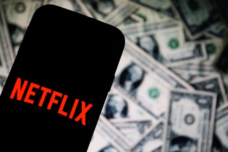 In this photo illustration a Netflix app logo is displayed on a smartphone with dollar bills in the background.