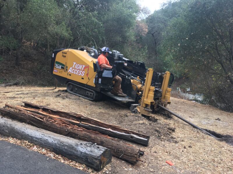 A man operates a piece of heavy machinery that installs fiber cables underground.