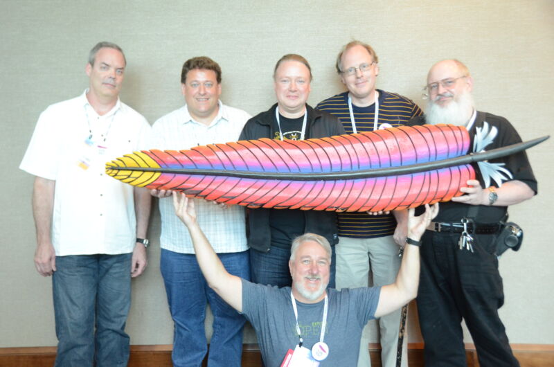 Group of men holding up the Apache Software Foundation's logo feather.