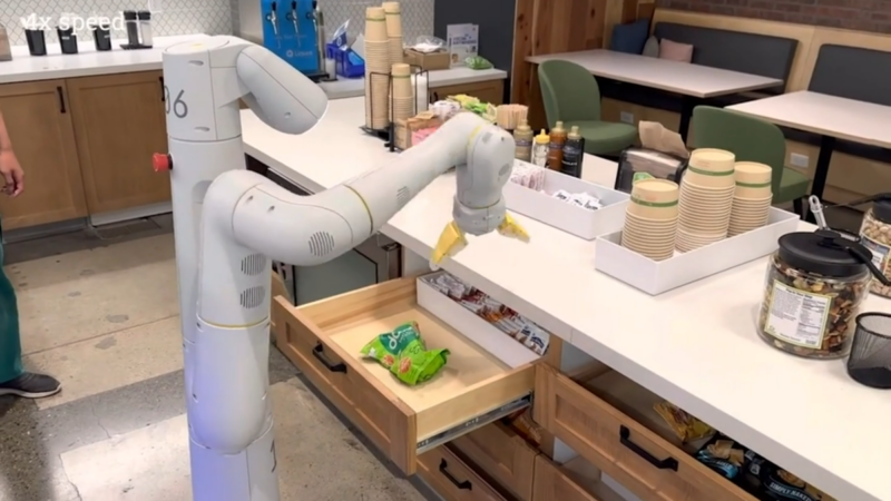 A robotic arm controlled by PaLM-E reaches for a bag of chips in a demonstration video.