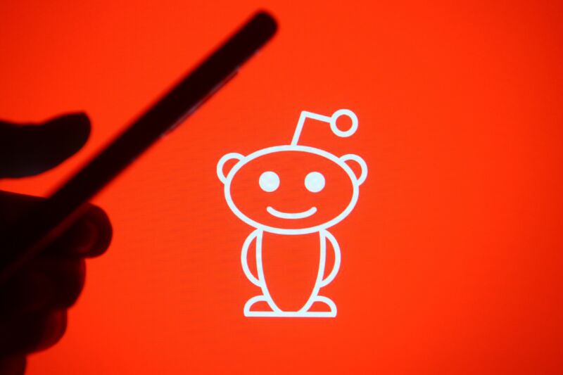 Reddit mascot in front of silhouetted phone