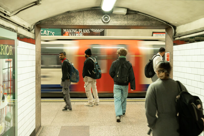 Commuters wait on the platform as a Central Line tube train arrives at Liverpool Street London Transport Tube Station in 2023.