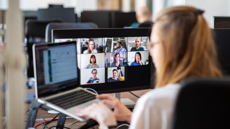 Woman discussing work on video call with team members at office