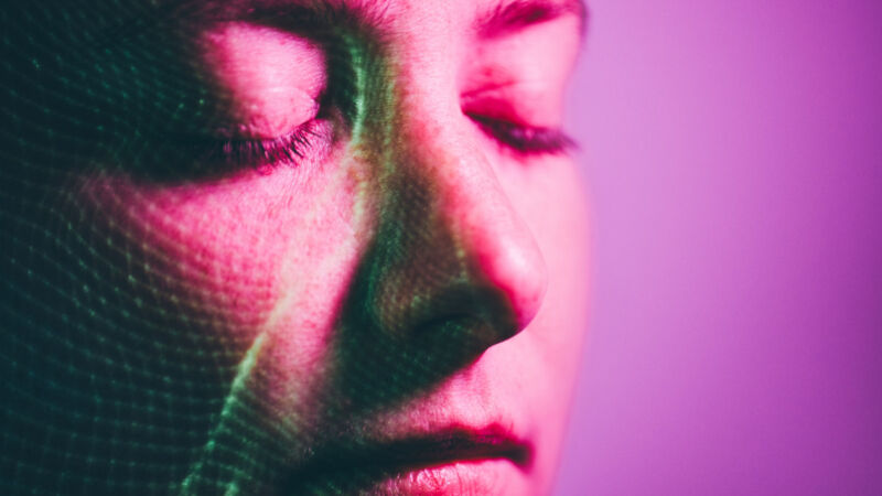 A stock photo illustration of a person's face lit with pink light.